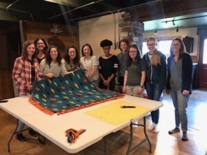 Students show a new blanket spread out on a table