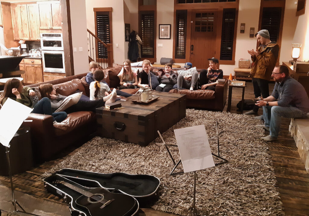 Teens hang out in the living room of a cabin during a youth retreat